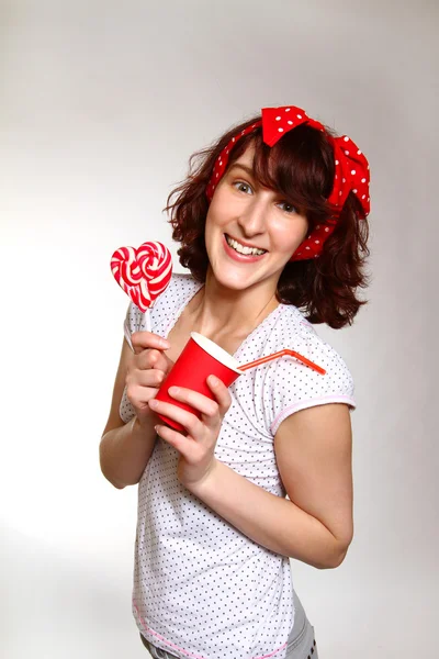 Mujer joven feliz con una piruleta y una taza aislada en una b gris —  Fotos de Stock