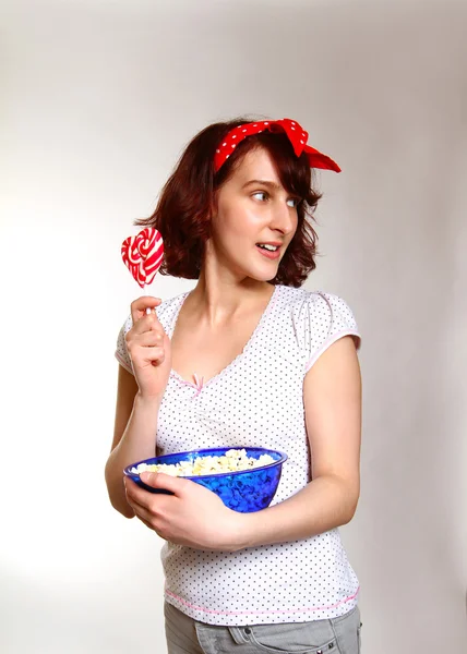 Interested girl with lollipop and popcorn watching isolated on a — Stock Photo, Image