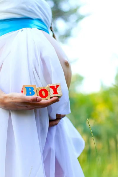 Close-up da barriga de uma mulher grávida segurando cubos menino para fora — Fotografia de Stock