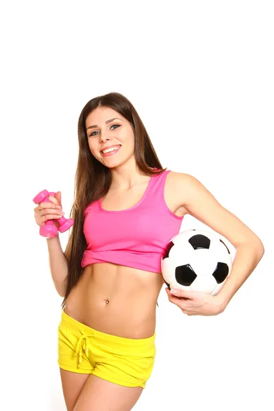 Симпатичная фитнес-девушка позирует с гантелями и футбольным мячом на w — стоковое фото