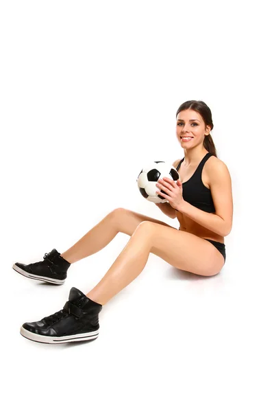 Menina sexy está sentado com uma bola de futebol em um fundo branco — Fotografia de Stock