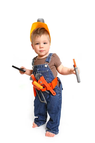 Niño en un casco naranja con herramientas y un teléfono móvil encendido — Foto de Stock