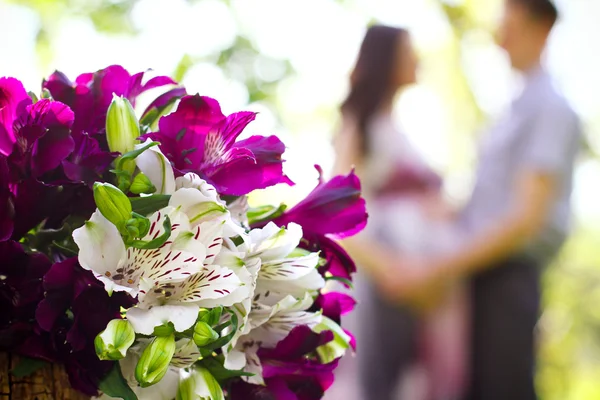 Feliz casal grávida e buquê de flores em primeiro plano Fotos De Bancos De Imagens
