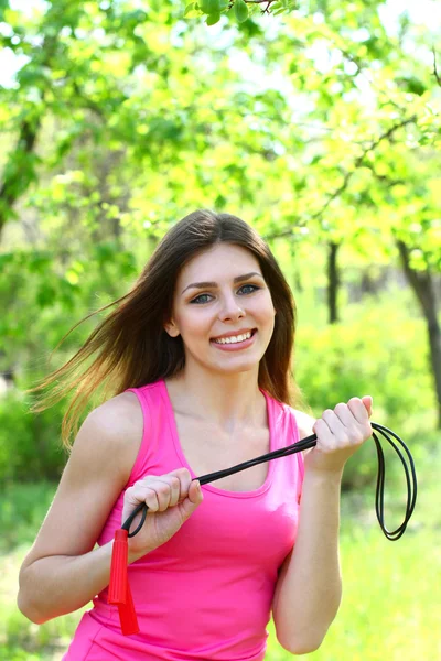 Girl posing with a skipping rope on the background of trees — Stock Photo, Image