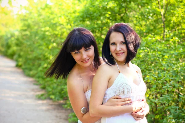 Twee gelukkige brunette in een zomer park — Stockfoto