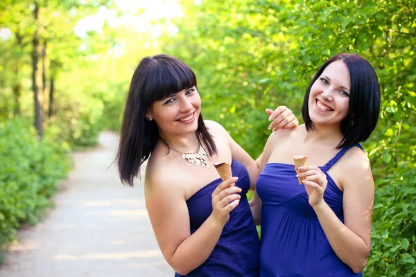 Twee gelukkige vrouwen met consumptie-ijs in de zomer park — Stockfoto