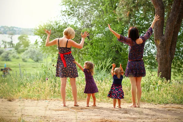 Two mothers with their daughters on the field in summer Royalty Free Stock Images