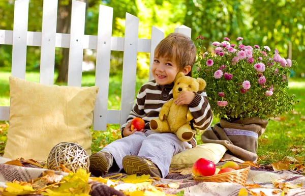 Liten pojke kramas en nallebjörn i höst park — Stockfoto