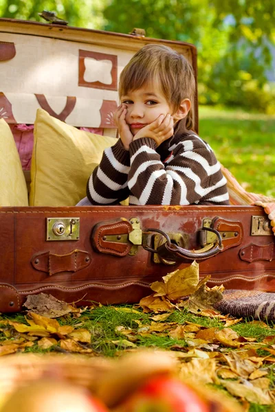 Menino triste sentado em uma mala velha — Fotografia de Stock