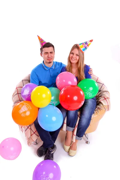 Двоє друзів сидять на дивані з капелюхами і повітряними кульками — стокове фото