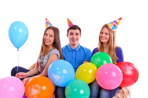 Tres amigos en sombreros con globos sentados en el sofá —  Fotos de Stock