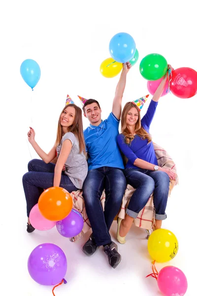 Trois amis en chapeaux avec des ballons assis sur le canapé — Photo