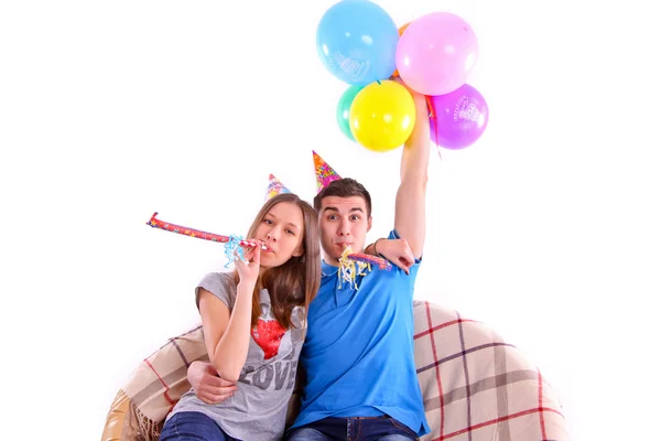 Couple avec chapeaux et ballons assis sur le canapé isolé — Photo