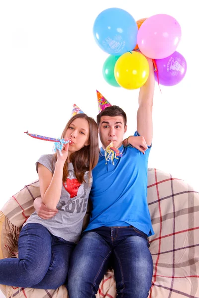 Pareja con sombreros y globos sentados en el sofá —  Fotos de Stock