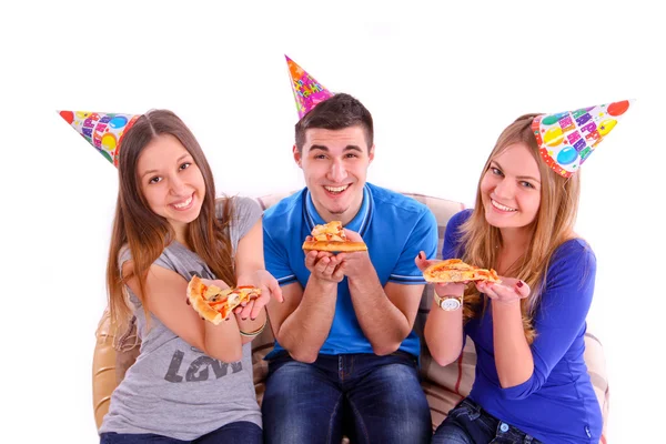 Three friends sitting on a sofa and eating pizza — Stock Photo, Image