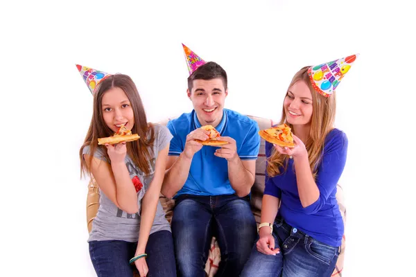 三个朋友坐在一张沙发上，一边吃比萨饼 — 图库照片