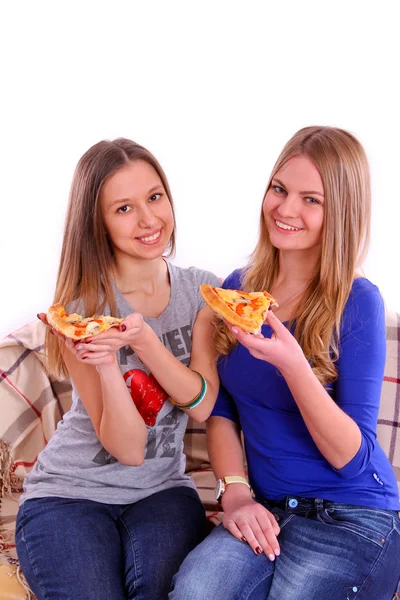 Two girls sitting on a sofa and eating pizza — Stock Photo, Image