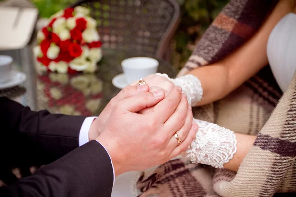 Couple holding hands at wooden table — Stock Photo, Image