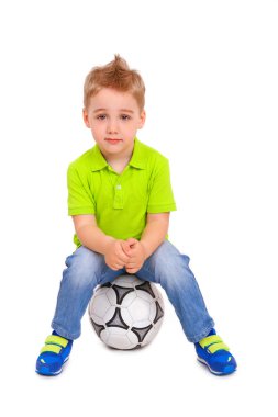 bir futbol topu üzerinde oturan küçük çocuk