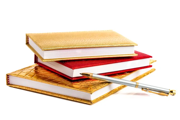 Золотые и красные блокноты с серебряной ручкой — стоковое фото