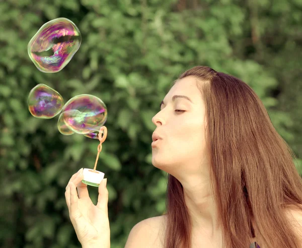 Pretty woman inflating soap-bubbles — Stock Photo, Image