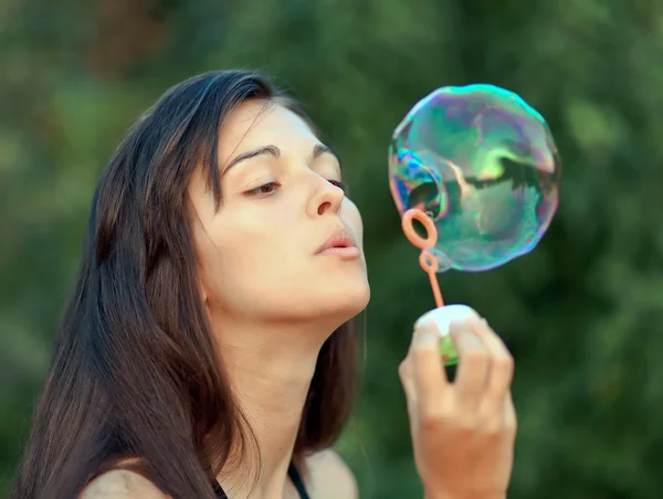 Pretty woman inflating soap-bubbles — Stock Photo, Image