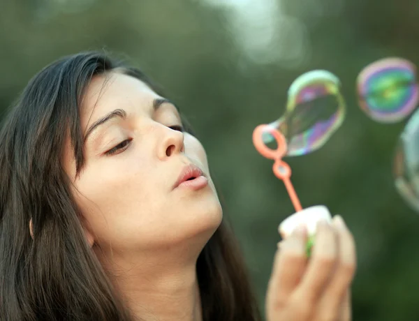 Pretty woman inflating soap-bubbles — Stock Photo, Image