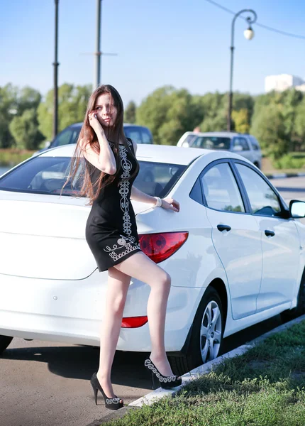 Beyaz spor arabanın yakınında duran ve telefonla konuşmak güzel bir genç kadın — Stok fotoğraf