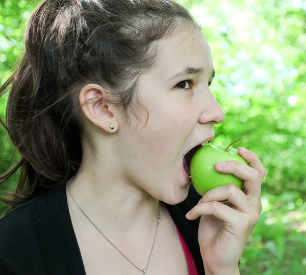 Bruna giovane ragazza mangiare mela nel parco estivo — Foto Stock