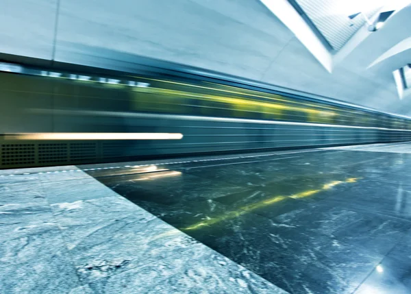 Perspectiva amplia vista angular de la moderna luz azul iluminada y amplia estación de metro público de mármol con rápido rastro borroso de tren en movimiento de tráfico en fuga —  Fotos de Stock