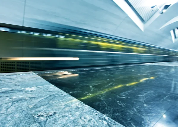 De groothoek perspectief bekijken van moderne licht blauw verlichte en ruime openbare marmeren metrostation met snelle wazig spoor van trein in verdwijnende verkeer beweging — Stockfoto