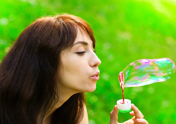 Portrait of attractive young girl inflating colorful soap bubble — Stock Photo, Image