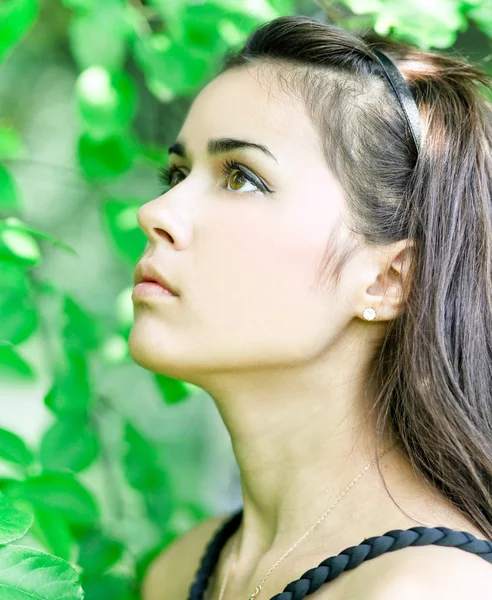 Portrait of beautiful cute young girl yearning in leafage outdoo — Stockfoto