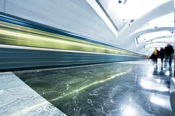 Široký úhel perspektivy pohled na moderní světle modré osvětlené a prostorné veřejné mramorové stanice metra se rychle rozmazané stopy vlaku v mizející přenos pohybu — Stock fotografie