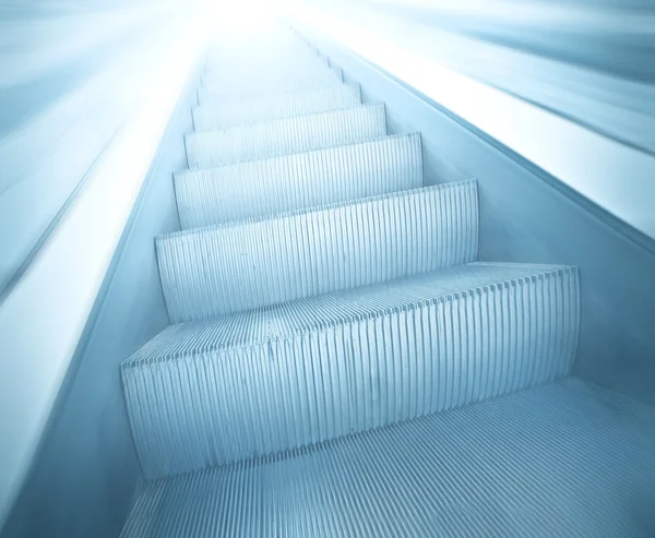 Perspectiva amplia vista angular de la moderna luz azul iluminada y espaciosa escalera mecánica comercial móvil de alta velocidad con pista borrosa rápida de barandilla en movimiento de tráfico de fuga en el corredor del aeropuerto —  Fotos de Stock