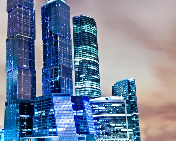 Panoramic and perspective wide angle view to steel blue background of glass high rise building skyscrapers in modern futuristic downtown at night Business concept of successful industrial architecture — Stock Photo, Image