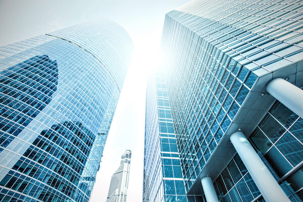 Panoramic and prospective wide angle view to steel light blue background of glass high rise building skyscraper commercial modern city of future. Business concept of successful industrial architecture