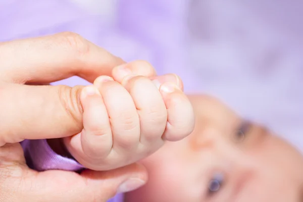 Baby catching mother 's finger — стоковое фото