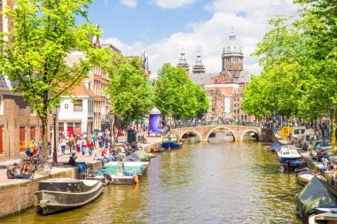 Amsterdam'da bir kanal tarafından yürüyen turist