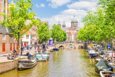 Amsterdam'da bir kanal tarafından yürüyen turist