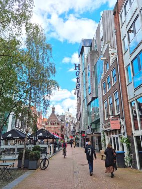 Amsterdam, Hollanda - 04 Ekim 2021: Nieuwezijds Voorburgwal caddesinde yürüyen insanlar. Cadde kuzeyden güneye, Merkez İstasyonu ve Baraj Meydanı 'nı birbirine bağlıyor..