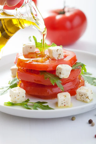 Vierte aceite de oliva sobre ensalada con tomates de res y feta — Foto de Stock