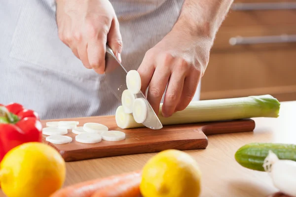 Chef cutting leek in kitchen — Stock Photo, Image