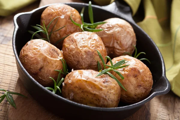 Baked potatoes with rosemary in black pan — Stock Photo, Image