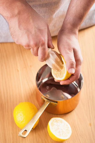 Mann drückt Zitrone in einen Kupfertopf — Stockfoto