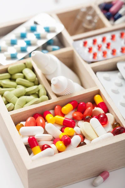 Pilules médicales et ampules dans une boîte en bois — Photo