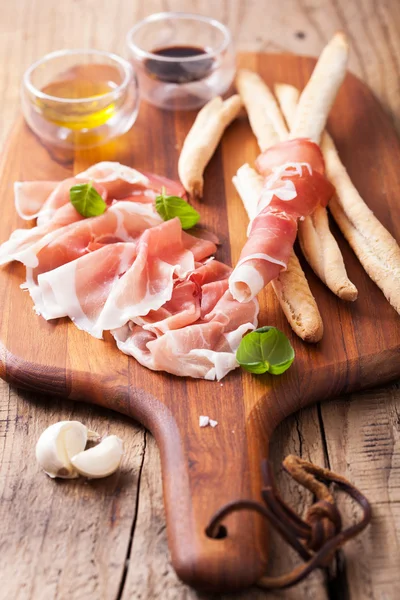 Italian prosciutto ham grissini bread sticks olive oil — Stock Photo, Image
