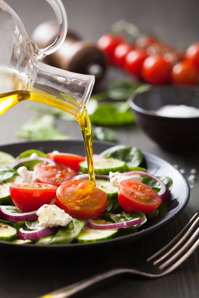 Наливаємо оливкову олію на салат з помідорами та огірком — стокове фото