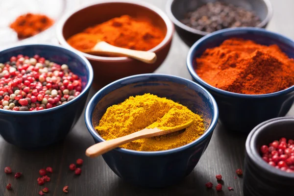 Specerijen in kommen: curry, roze en zwarte peper, paprika poeder — Stockfoto