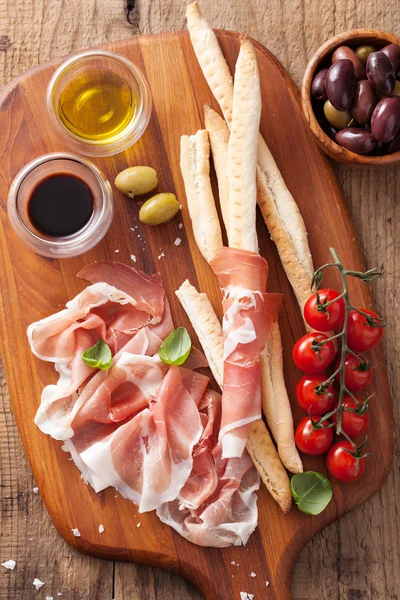 Prosciutto crudo grissini bastoncini di pane pomodoro olio d'oliva — Foto Stock